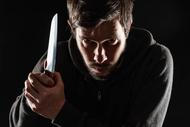 istock Scary and evil maniac or murderer with knife on black background. 1317405688