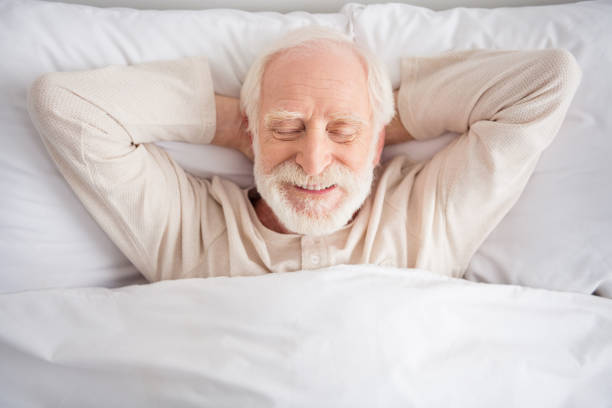 Top above high angle photo of aged man sleep rest relax bedtime comfort cozy happy positive wear pajamas hands behind head home Top above high angle photo of aged man sleep rest relax bedtime comfort cozy happy positive wear pajamas hands behind head home. old man pajamas photos stock pictures, royalty-free photos & images