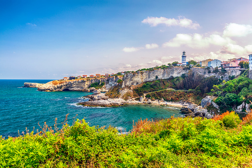 white lighthouse on top of a rocky cliff with white walls surrounding it and the sea in the background, Cavalleria cape lighthouse, Fornells, Menorca Spain, horizontal