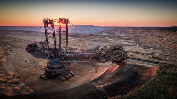 AERIAL: Lignite surface mine with  giant bucket-wheel excavator Aerial shot of a giant open pit lignite mine Hambach in Germany. Large bucket excavator mining machinery. Moody light at sunset. mining natural resources photos stock pictures, royalty-free photos & images