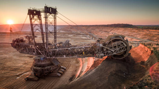 Coal Mining, Lignite Surface Mine - AERIAL Aerial shot of a large bucket wheel excavator excavating soil in an open pit lignite mine in Germany at sunset. open pit mining stock pictures, royalty-free photos & images