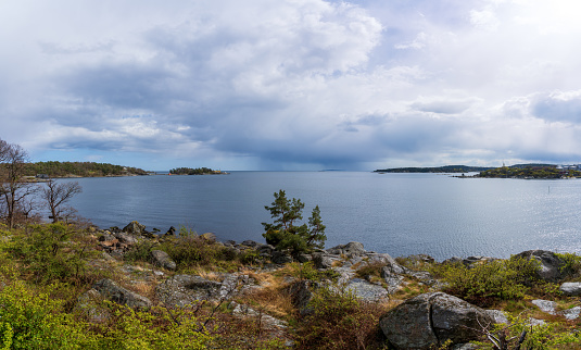 Dramatic spring weather with sun and dark rain clouds over the sea in Karlshamn, Sweden. Panoramic view.