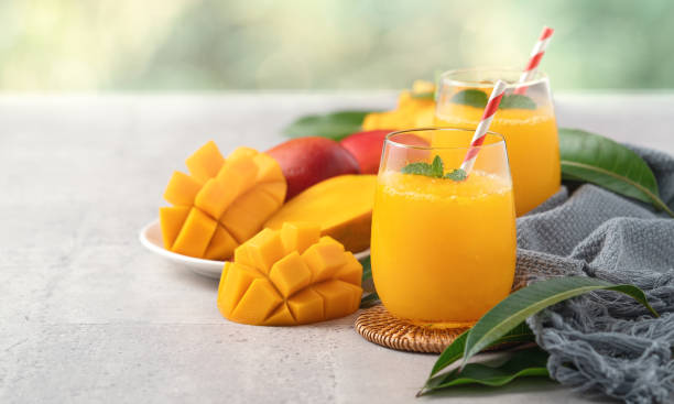 fresco hermoso batido de jugo de mango delicioso en una taza de vidrio sobre fondo de mesa gris. - cocktail orange cup juice fotografías e imágenes de stock