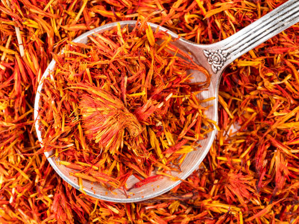 silver spoon on dried safflower petals closeup top view of silver spoon on pile of dried safflower petals closeup substitute for saffron stock pictures, royalty-free photos & images