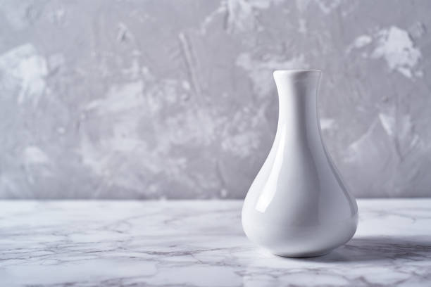 istock White vase isolated on plaster grey wall background, copy space. Home decor 1317414398