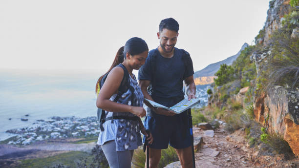istock Shot of a young couple using a guide book to complete a hike in a mountain range 1317416946