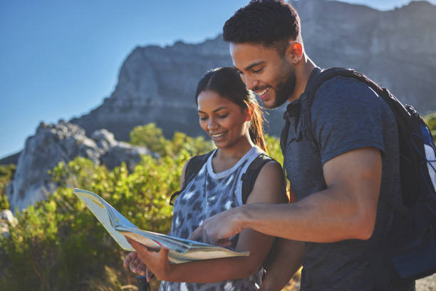 istock Shot of a young couple using a guide book to complete a hike in a mountain range 1317416957