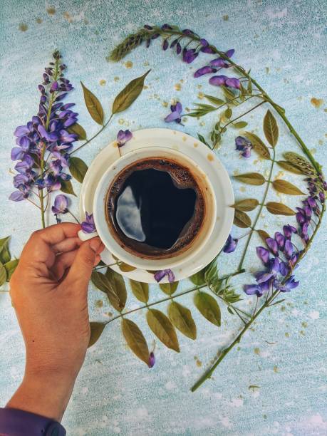 Cup of morning hot coffee on a blue background with beautiful white flowers as a daily ritual. Top view. Flat lay. Still life.