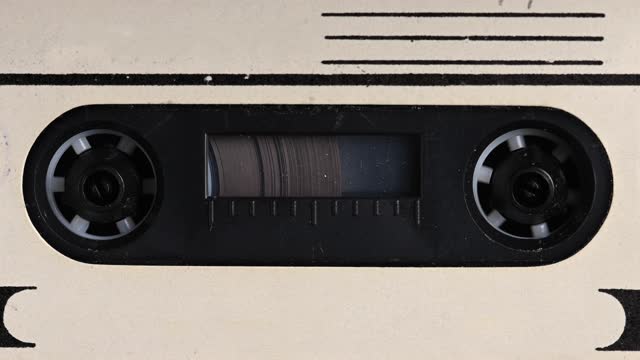 Close-up A tape recorder is playing an audio cassette. Close-up. A vintage audio cassette spins on a blank label tape used to record sound in a retro cassette player. Recording of conversations.