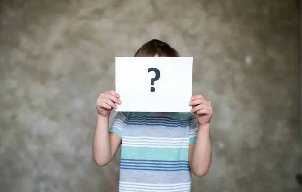 Photo of Boy holding a paper with a question mark