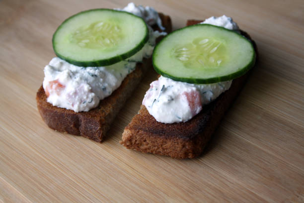 istock Cottage cheese dip with cucumber slices on black bread toast. Breakfast. 1317421890