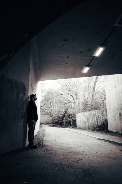 istock Lonely man standing against wall in urban tunnel 1317422061