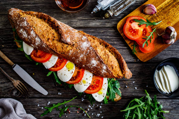 bánh sandwich mozzarella - bánh mì baguette pháp giòn với mozzarella, arugula và cà chua thái lát trên bàn gỗ - caprese sandwich bức ảnh hình ảnh sẵn có, bức ảnh & hình ảnh trả phí bản quyền một lần