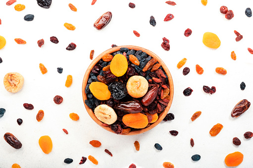 Healthy food snack: natural sun dried fruits mix in bowls on white background, top view