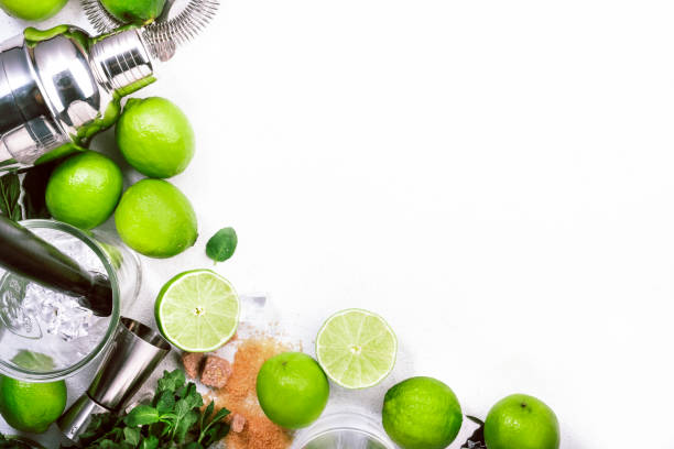 istock Mojito cocktail preparing ingredients: lime, mint, ice and bar tools, white background, top view 1317426833