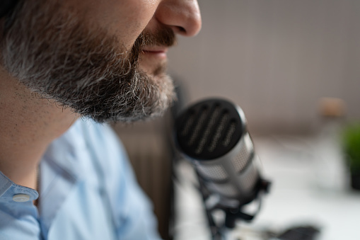 Close-up of an unrecognizable Caucasian male commentator on a podcast.