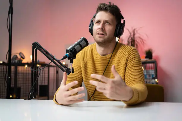 Portrait of a young Caucasian man talking on the microphone at the radio station.