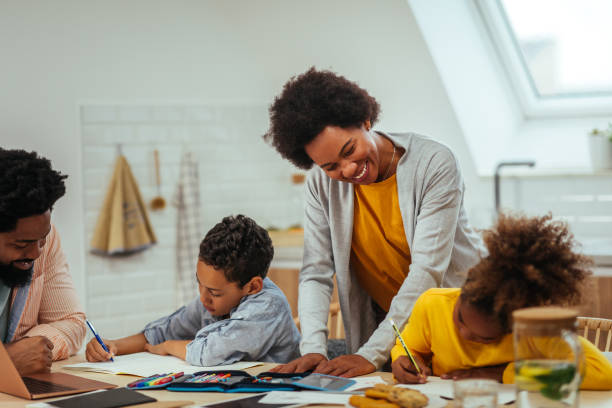 istock Two afro children and their parents doing homework together while sitting at the table 1317430672