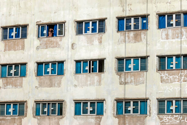 bangkok  thailand february 7  -2009   an unknown man looking out from a hotel with many windows and blue curtains in bangkok city in thailand