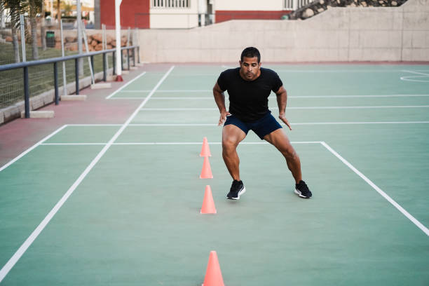 Hispanic man doing speed and agility cone drills workout session outdoors - Focus on man face stock photo