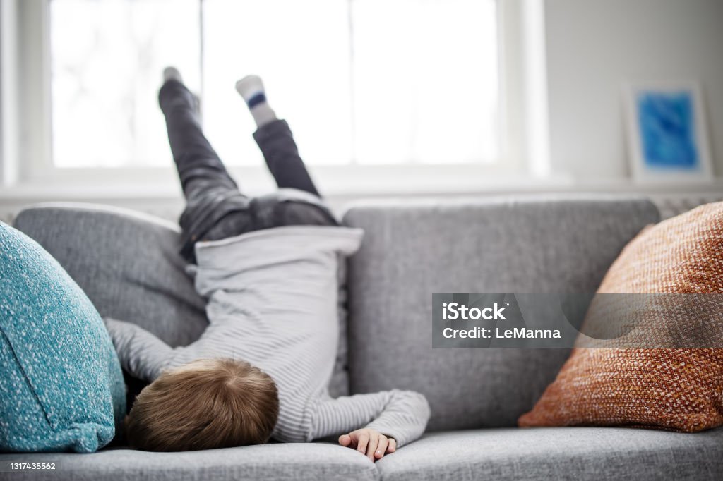 Cute child lying face down on the sofa Cute child lying face down on the sofa. Tired boy after leisure activity and cheerful games. Boredom Stock Photo