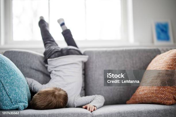 Cute Child Lying Face Down On The Sofa Stock Photo - Download Image Now - Boredom, Child, Boys