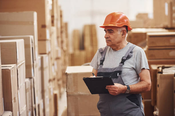 istock Senior storage worker in uniform and notepad in hands checks production 1317435721