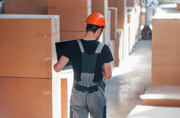 istock Storage worker in uniform and modern laptop in hands checks production 1317435824