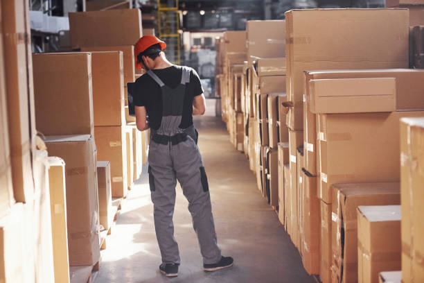 istock Storage worker in uniform and modern laptop in hands checks production 1317435902