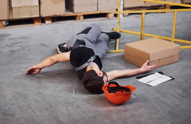 istock Warehouse worker after an accident in the storage. Man in uniform lying down on the ground 1317436317