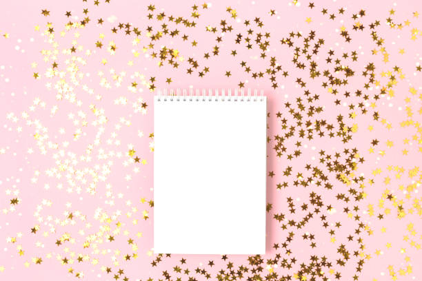 istock Notebook mockup on a pink background with gold stars confetti. 1317437834