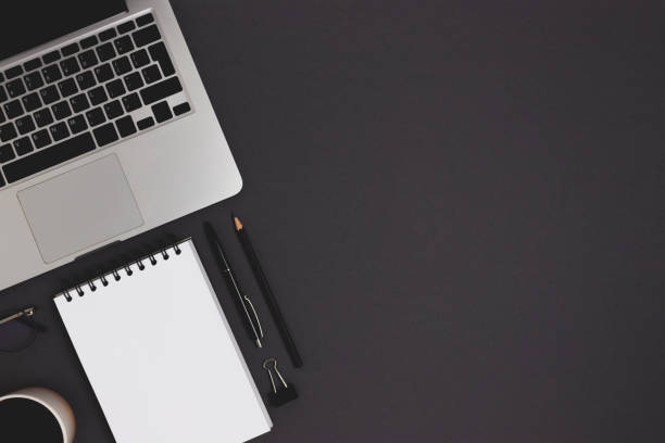istock Organized workspace with laptop and office supply on a black background. 1317437898