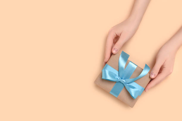 istock Female hands hold gift box on a beige background. 1317438497