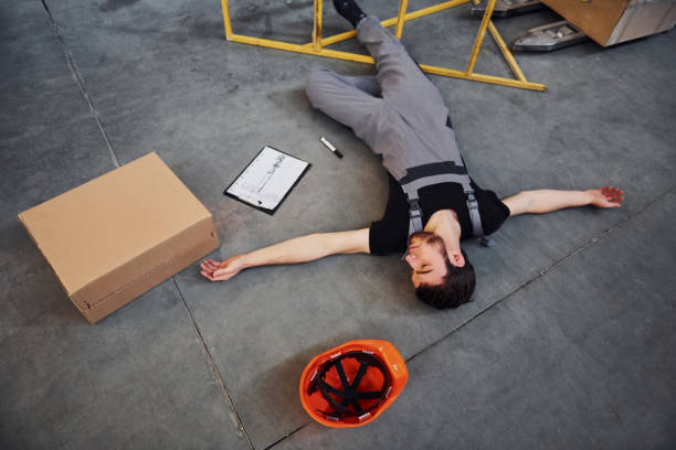 istock Warehouse worker after an accident in the storage. Man in uniform lying down on the ground 1317438781