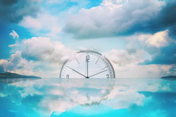 Photo of Clock that goes into the water. Cloudy sky. Reflection. Time limit concept. Business. Lifestyle.