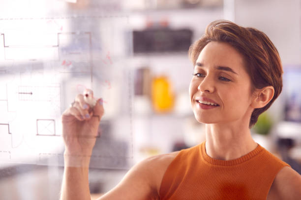 istock Female Architect In Office Making Notes On Building Blueprint On Transparent Screen 1317441864