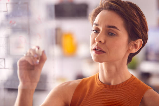 istock Female Architect In Office Making Notes On Building Blueprint On Transparent Screen 1317442441