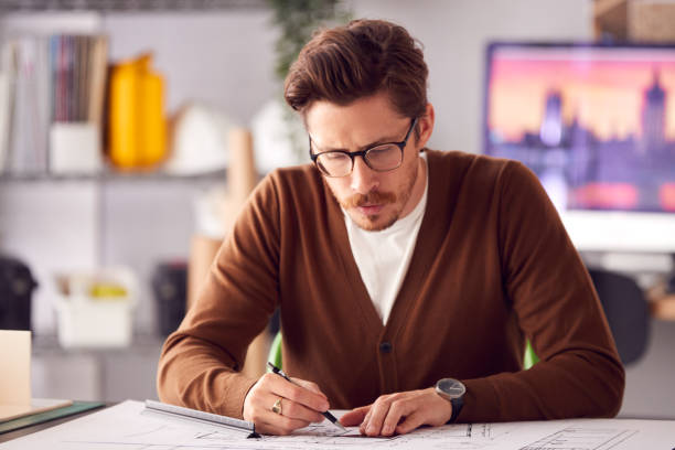 istock Male Architect At Desk In Office Amending Building Plans 1317442509