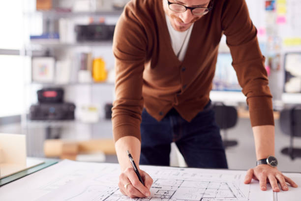 istock Male Architect Standing At Desk In Office Amending Building Plans 1317442722