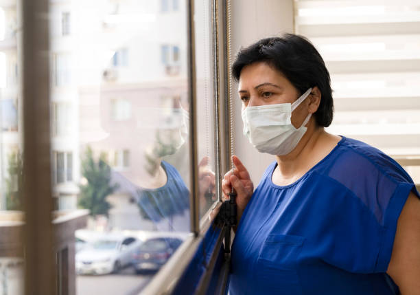 istock Senior woman wears protective face mask staying at home under quarantine 1317444107