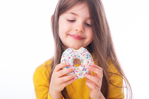 Sweet little girl eating white donut