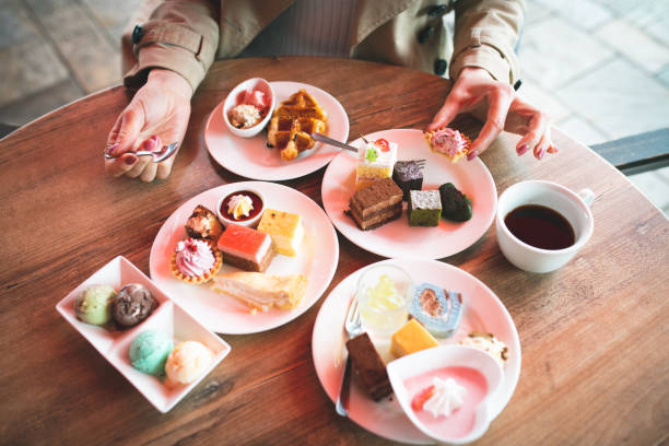 las mujeres comen muchos dulces - comer demasiado fotografías e imágenes de stock