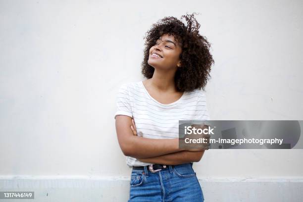 Happy Young African American Woman Smiling With Arms Crossed And Looking Away Against White Background Stock Photo - Download Image Now