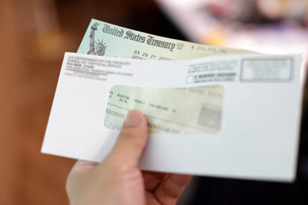 istock Man holding a tax refund check 1317449873