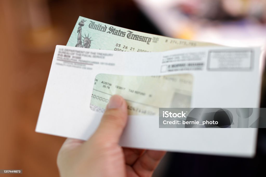 Man holding a tax refund check Man receives a tax refund check from the government; Indoor background Tax Stock Photo