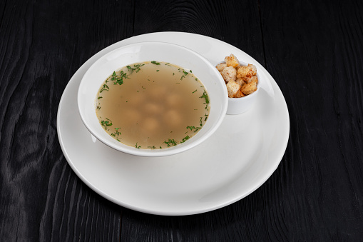 Chicken soup bouillon in a plate with chicken meatballs and croutons