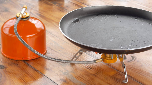 Black Frying Pan With Poured Oil Stands On Portable Camping Gas Stove stock photo