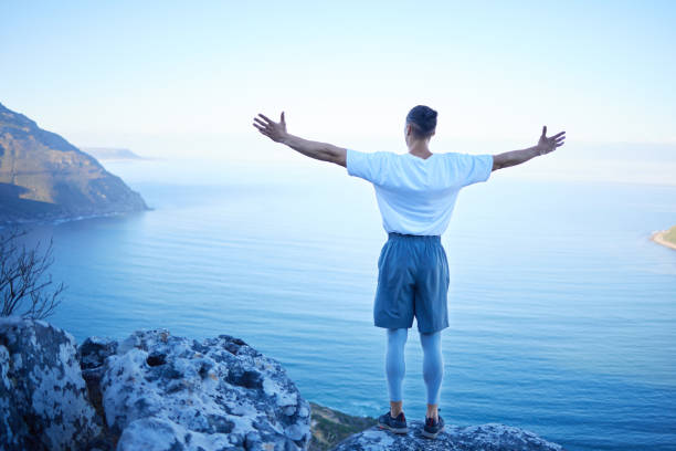 istock Rearview shot of an unrecognizable young man standing with his arms outstretched while looking at the ocean view from the mountain 1317457599