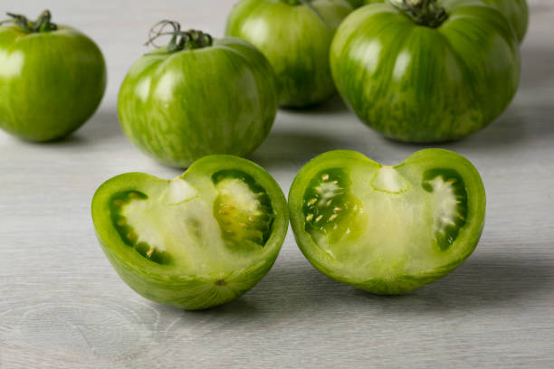 istock Whole and halved fresh green zebra tomato close up 1317459172