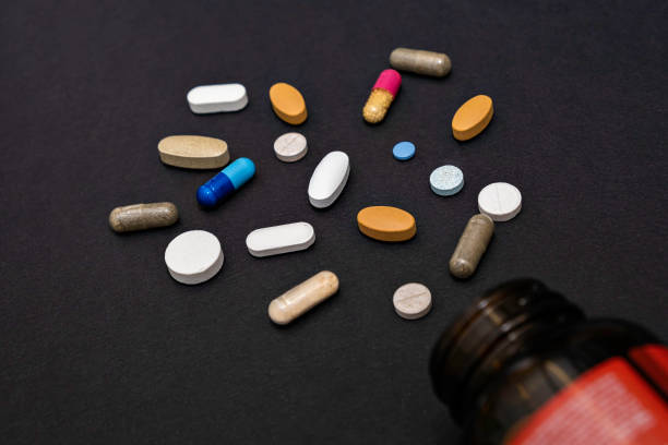 istock Close-up colorful assorted powder soft capsules pill vitamins and jar bottlesupplements on black background 1317460048